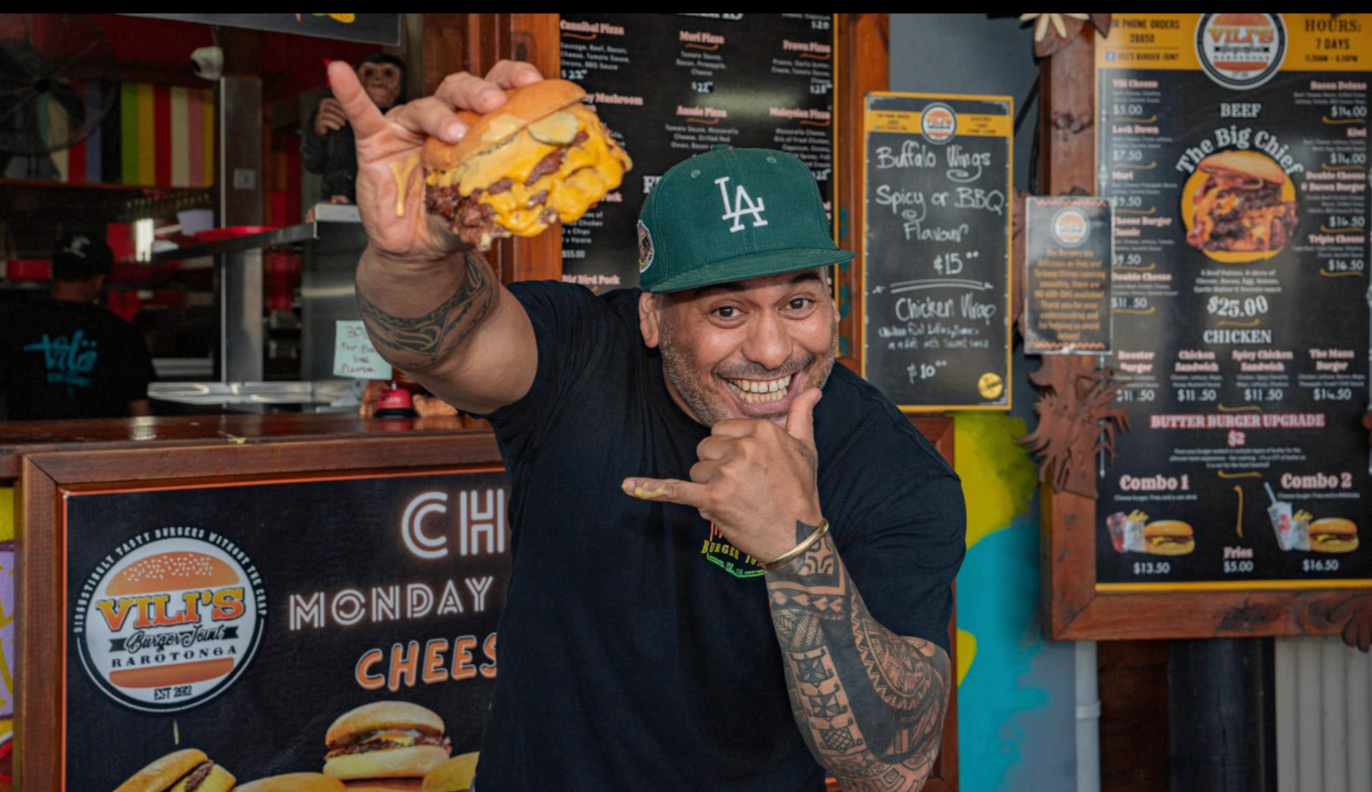 Vili — owner of Vili's Burger Joint, holding a Big Chief burger